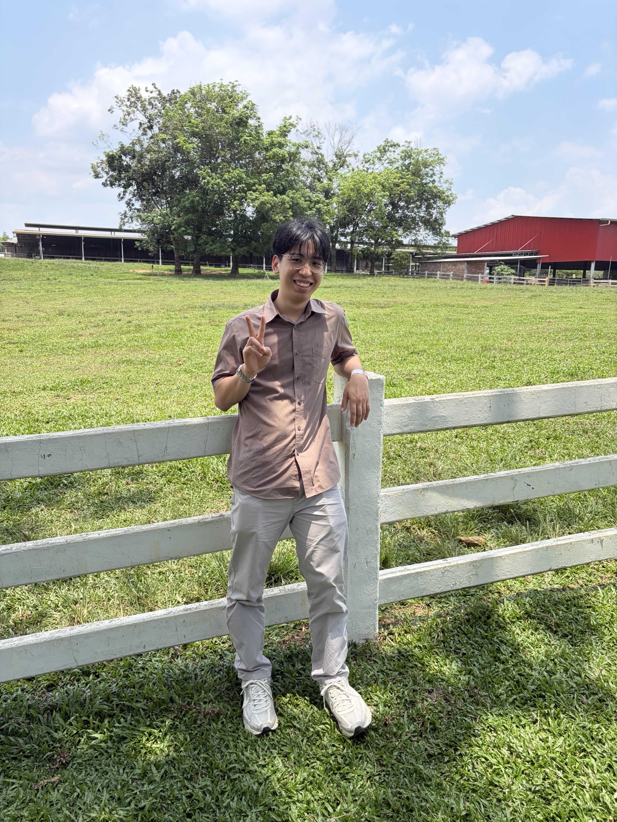 Leonard Su standing beside a white fence in a sunny field